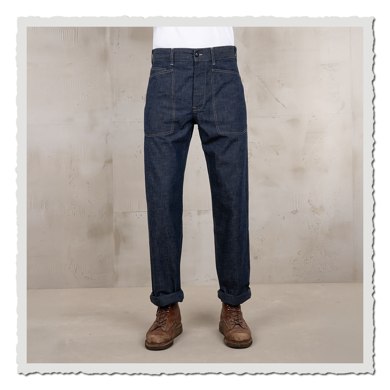 ndigoblaue Hose von vorn getragen, mit aufgekrempeltem Saum vor hellem Studiohintergrund.